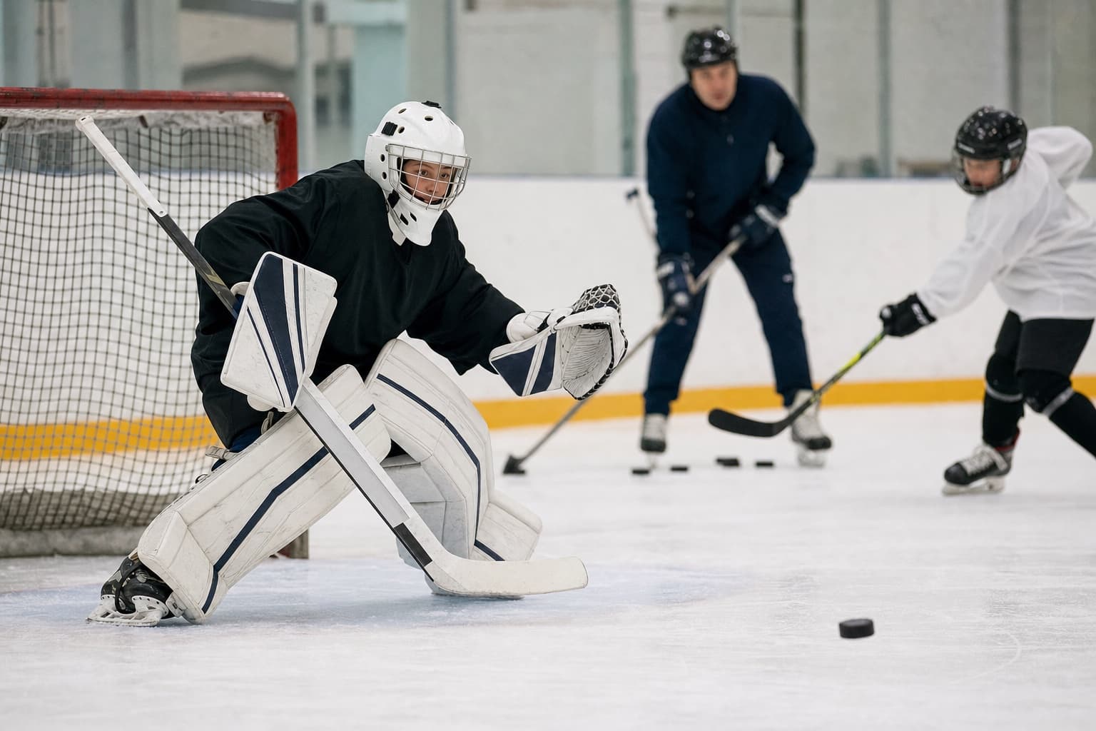 A young goaltender tracking a shot in the crease